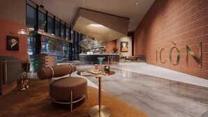 Een moderne lobby met een bar, zitplaatsen en een grote muur waarop het woord "ICON" staat.