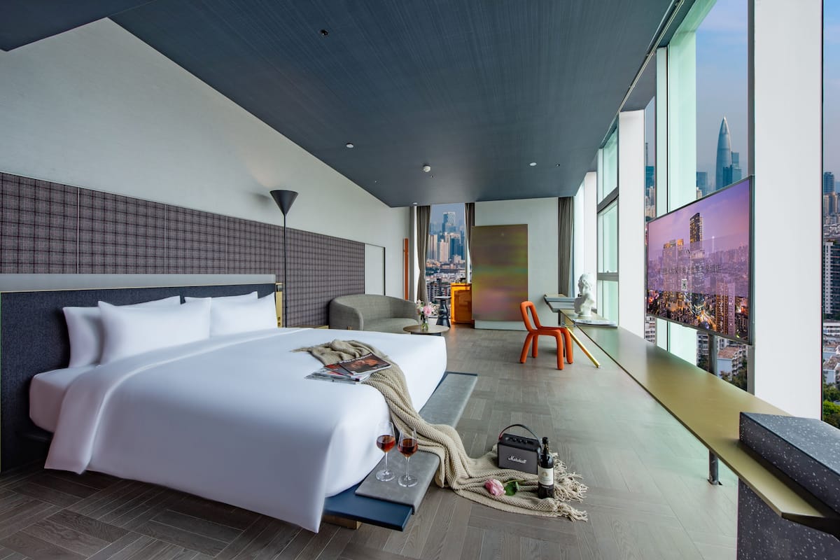 Una habitación de hotel moderna con una cama grande, un escritorio y vistas a la ciudad.