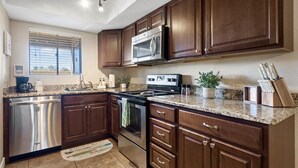 A modern kitchen with dark wood cabinets, stainless steel appliances, and granite countertops. - Paradise Valley Paradise/ Ground Unit (Phoenix)