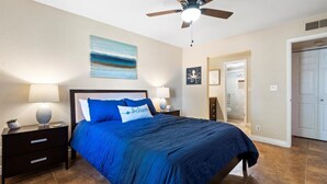 A bedroom with a bed, nightstands, a ceiling fan, a painting, and a door. - Paradise Valley Paradise/ Ground Unit (Phoenix)