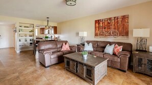 A living room with a brown leather sofa, a wooden coffee table, and a dining area in the background. - Paradise Valley Paradise/ Ground Unit (Phoenix)