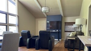 A living room with a flat-screen TV, leather chairs, a sofa, and a dining table. - Year round mountain retreat (Flagstaff)