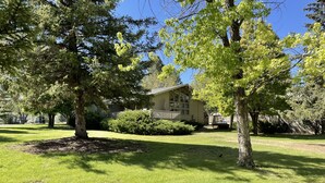 A house with a well-maintained lawn, surrounded by trees and a wooden fence. - Year round mountain retreat (Flagstaff)