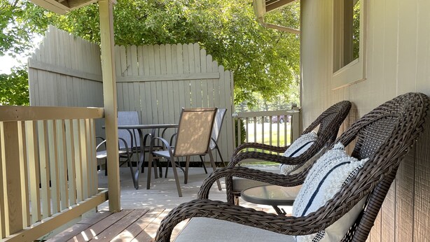 A wooden deck with wicker chairs and a table, a white picket fence, and a wooden building in the background. - Year round mountain retreat (Flagstaff)