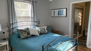 A bedroom with a metal bed frame, a blue bedspread, and a white nightstand. - Harmonious and inviting home- 3 bed, 2 bath ranch (Columbus)