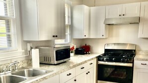 A kitchen with white cabinets, a stainless steel stove, a microwave, and a sink. - Harmonious and inviting home- 3 bed, 2 bath ranch (Columbus)
