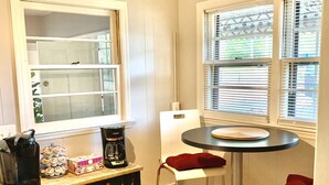 A small kitchen with a round table, two bar stools, a coffee maker, and a window with blinds. - Harmonious and inviting home- 3 bed, 2 bath ranch (Columbus)