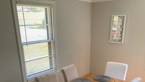 A dining room with a wooden table, white chairs, and a window with blinds. - Harmonious and inviting home- 3 bed, 2 bath ranch (Columbus)