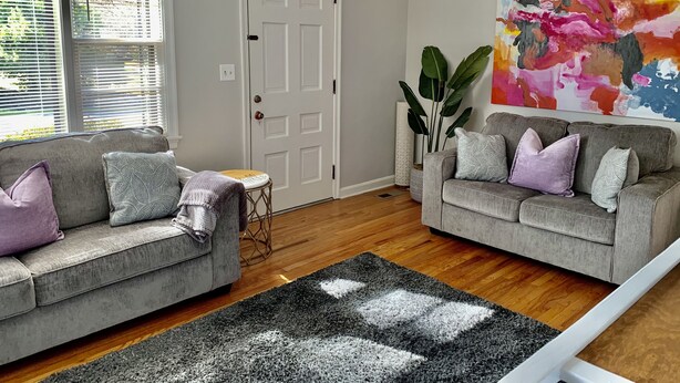 A living room with two grey sofas, a coffee table, a large abstract painting, and a ceiling fan. - Harmonious and inviting home- 3 bed, 2 bath ranch (Columbus)