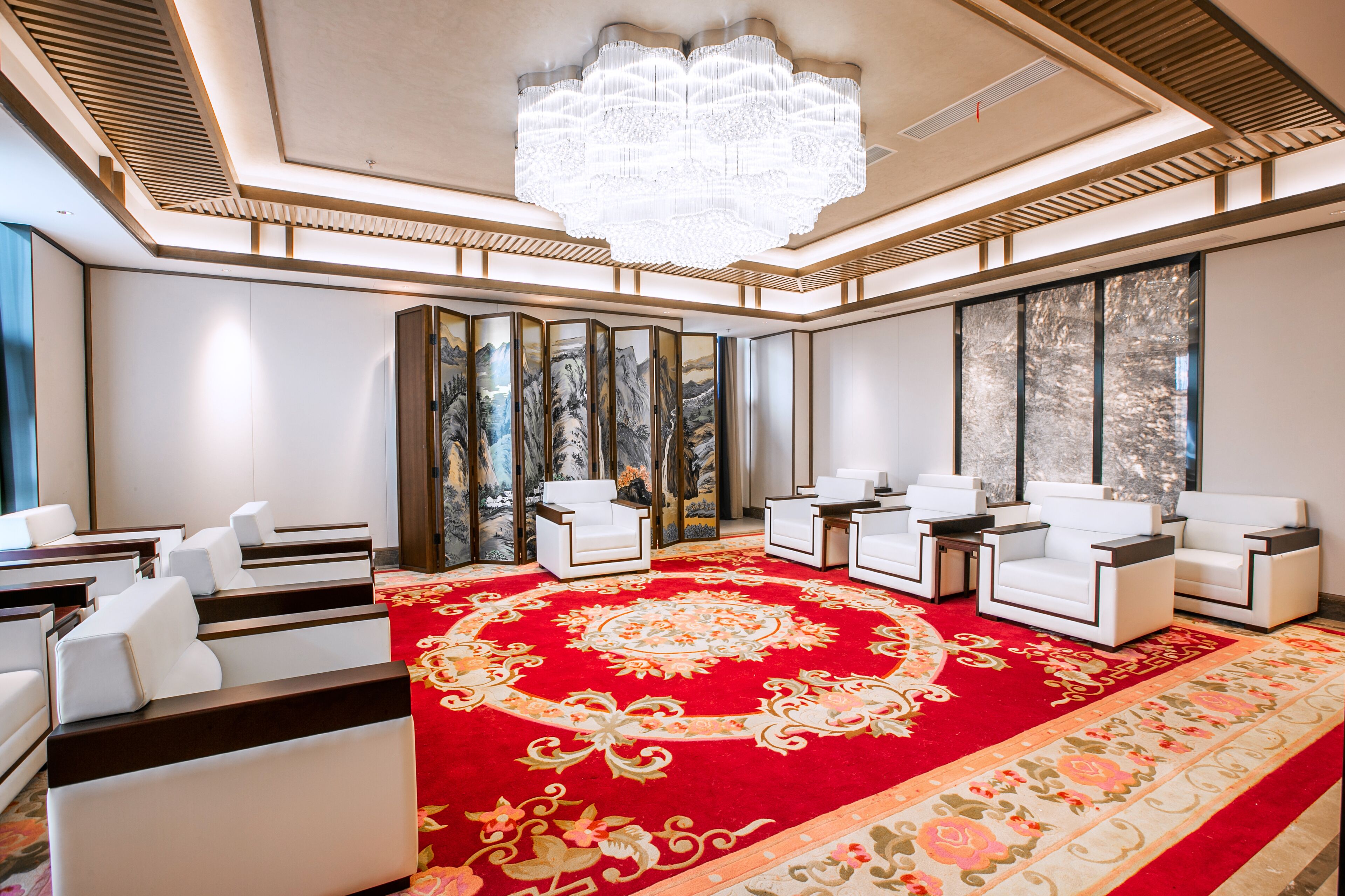 Une chambre luxueuse avec un tapis rouge, des canapés blancs et un grand lustre.
