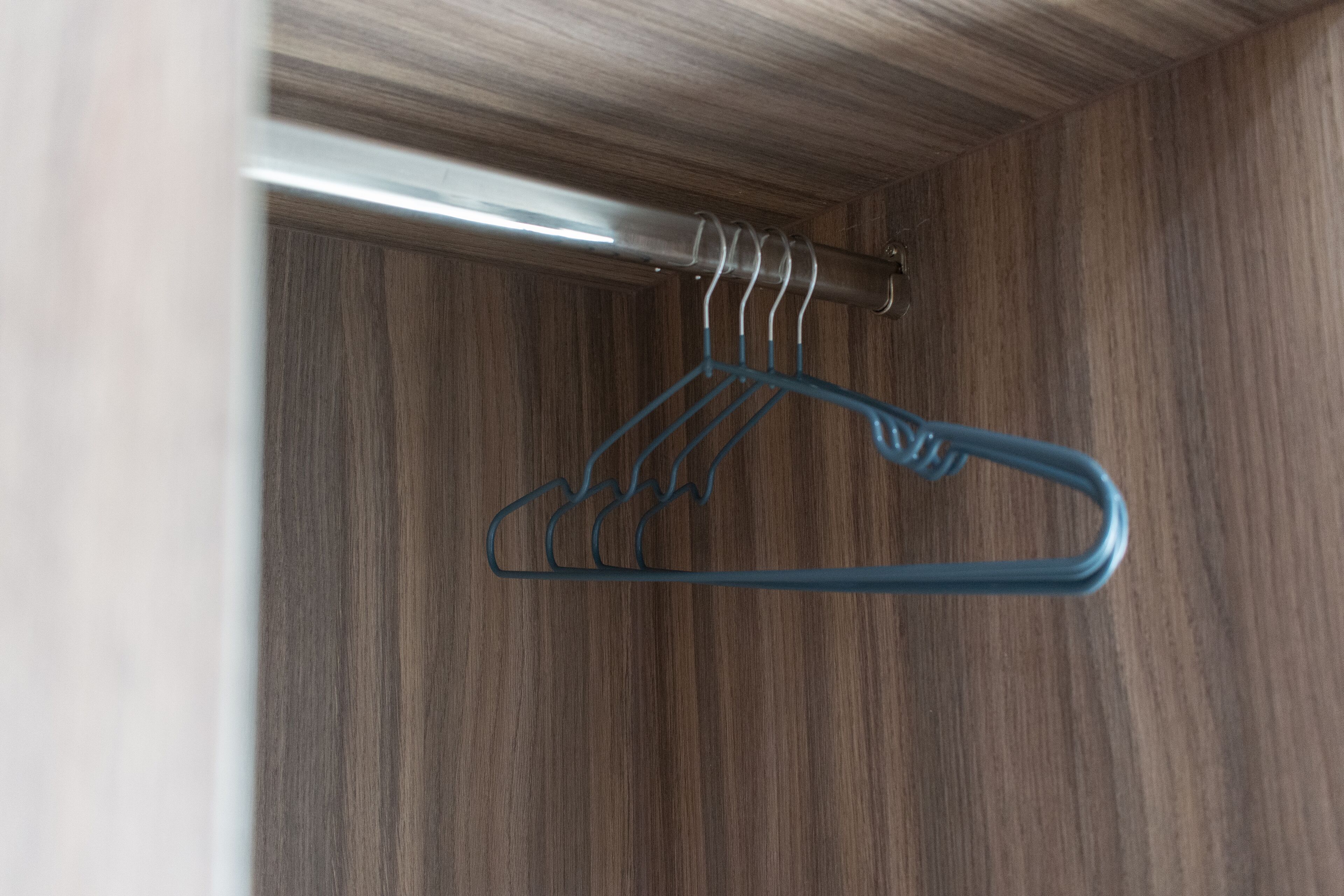 A wooden closet with a metal hanger rod.