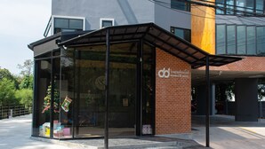 A modern hotel entrance with a glass booth, a brick facade, and a sign for the 'Doubled Hotel'. - Double D Hotel (Pak Kret)