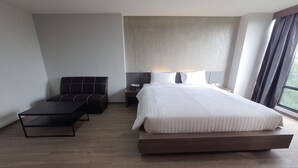 A modern hotel room with a large bed, a sofa, a small table, and a nightstand. - Double D Hotel (Pak Kret)