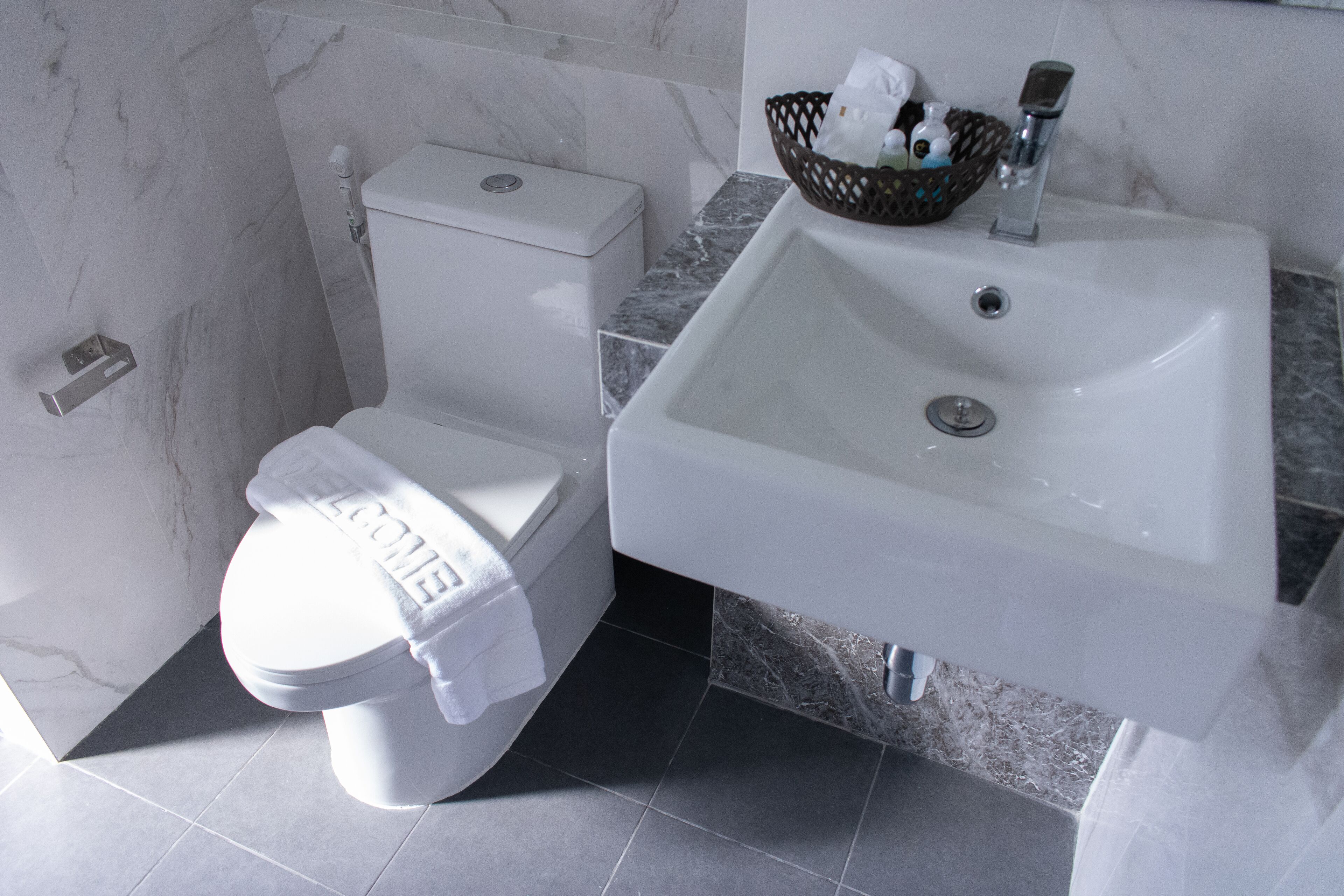 A modern bathroom with a toilet, sink, and marble tiles.