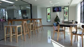 A modern interior with a glass wall, wooden chairs, a Christmas tree, and a TV on the wall.