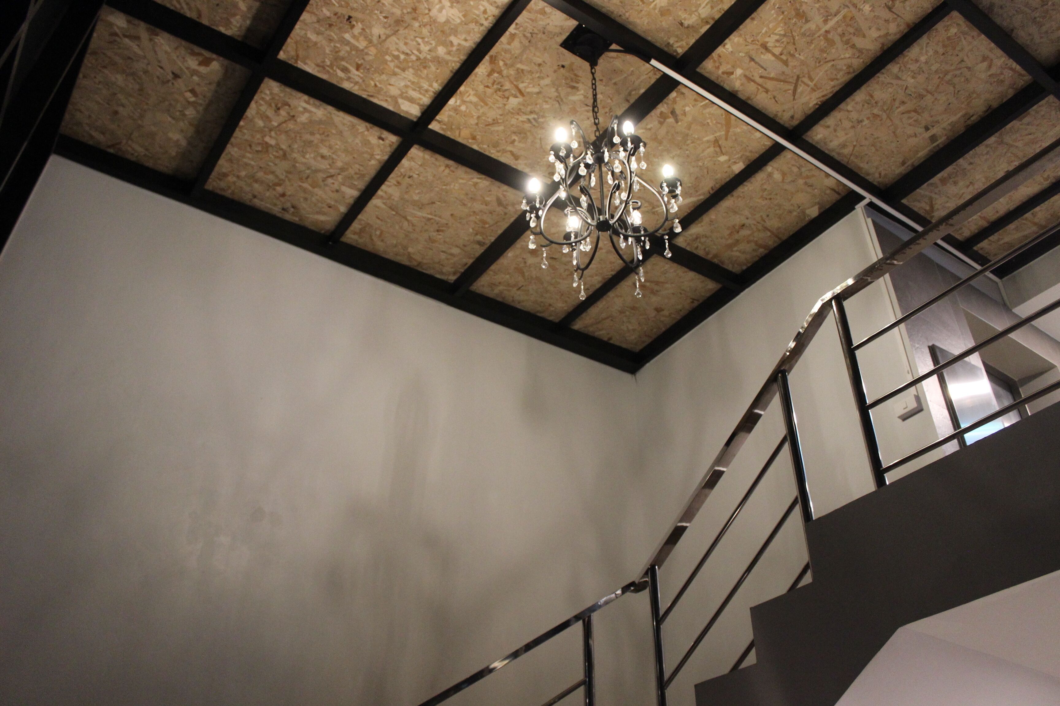 Una escalera con techo de madera y un candelabro.