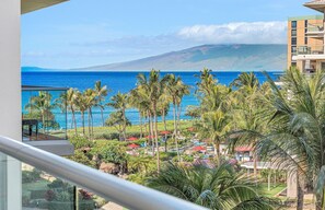 A resort view with a pool, palm trees, and a mountain in the background.