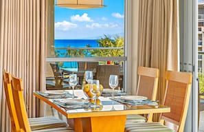 A dining area with a table set for four, chairs, and a view of the ocean.