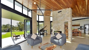 A modern living room with two grey sofas, a coffee table, and a stone fireplace. - Stunning home on 5 acres with Infinity Pool & Fireplace (Herron)