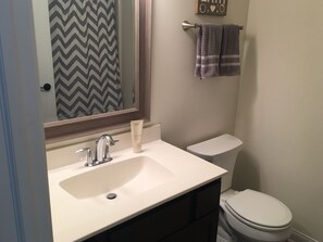 Een bad/douchecombinatie, handdoeken, zeep, toiletpapier