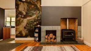 A living room with a fireplace, a large painting on the wall, and a bookshelf. - Court House Hideaway by Your Innkeeper Mudgee (Mudgee)