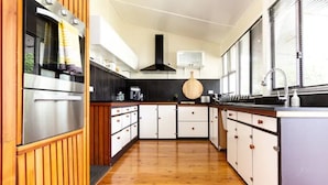 A modern kitchen with wooden cabinetry, a stainless steel oven, and a large window providing natural light. - Court House Hideaway by Your Innkeeper Mudgee (Mudgee)