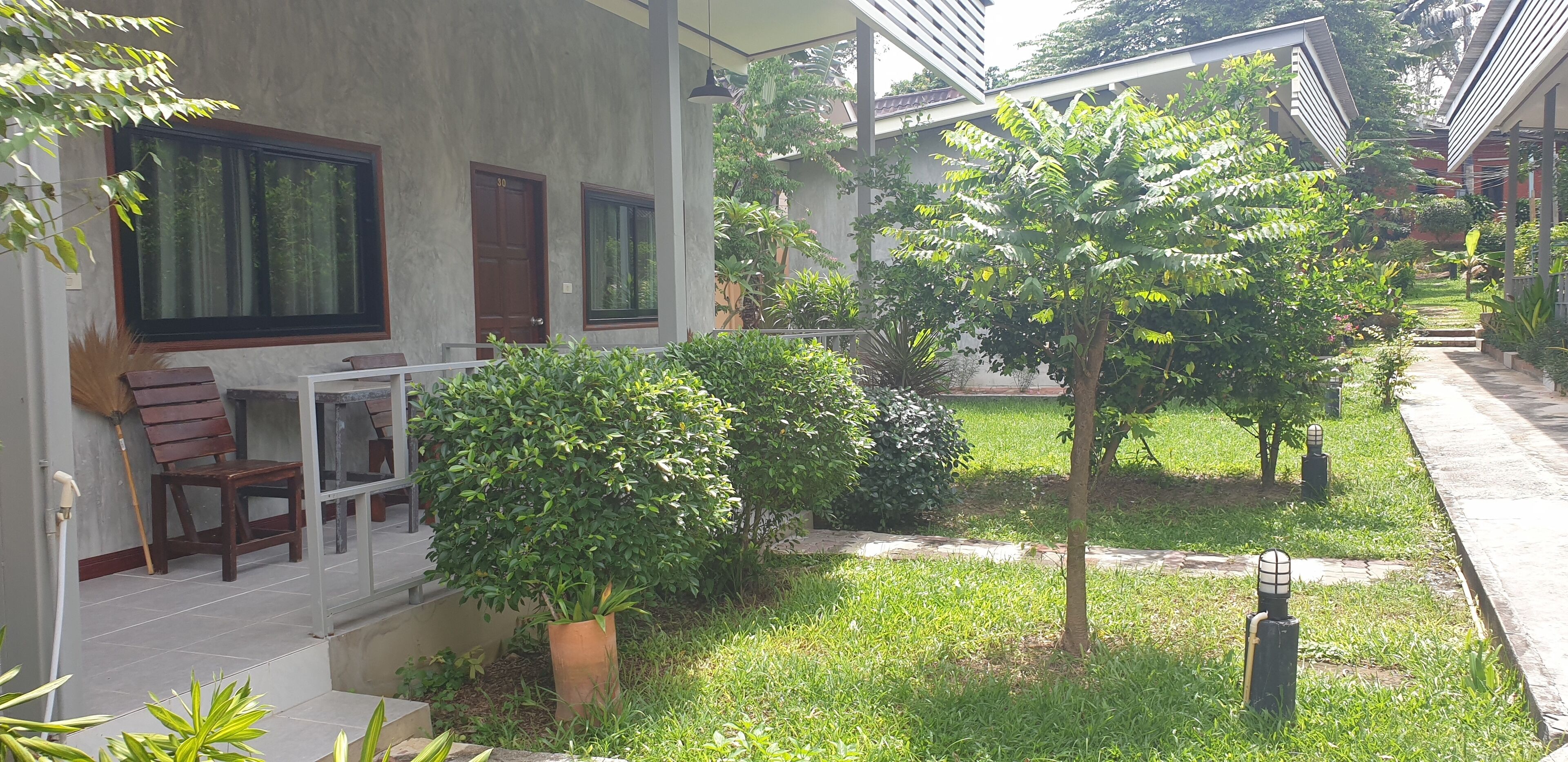 Une cour avec un espace aménagé pour s’asseoir, un pot de fleurs et un chemin menant à un bâtiment.