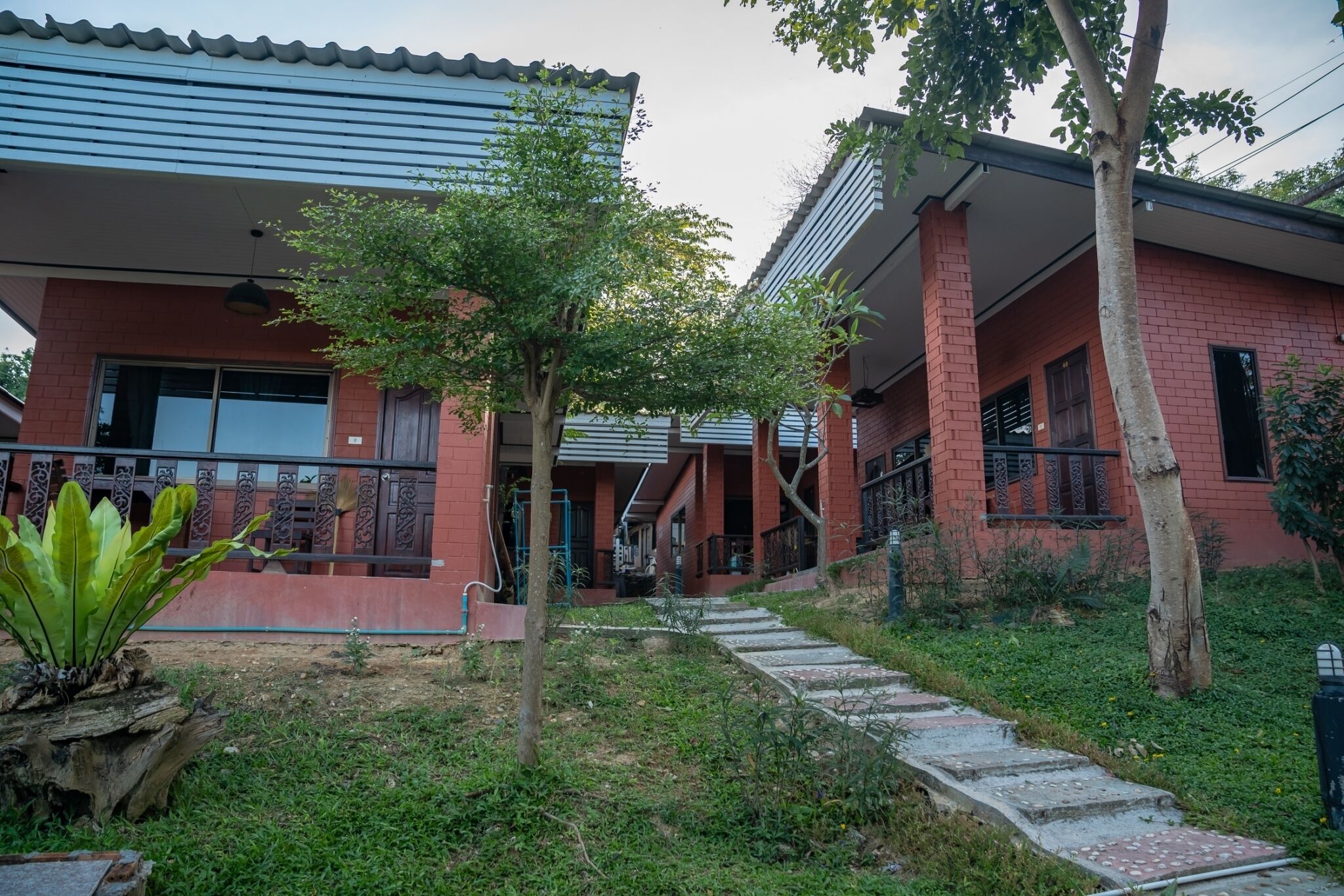 Un edificio de dos pisos con fachada de ladrillo rojo, un porche cubierto y un camino de concreto que lleva a la entrada.