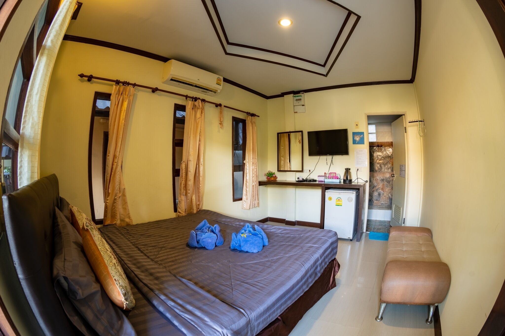 A hotel room with a bed, a desk, a TV, and a bathroom visible through an open door.