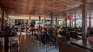 Ein Restaurant mit Holzbalkendecke, mehreren Tischen und Stühlen sowie einer Bar.