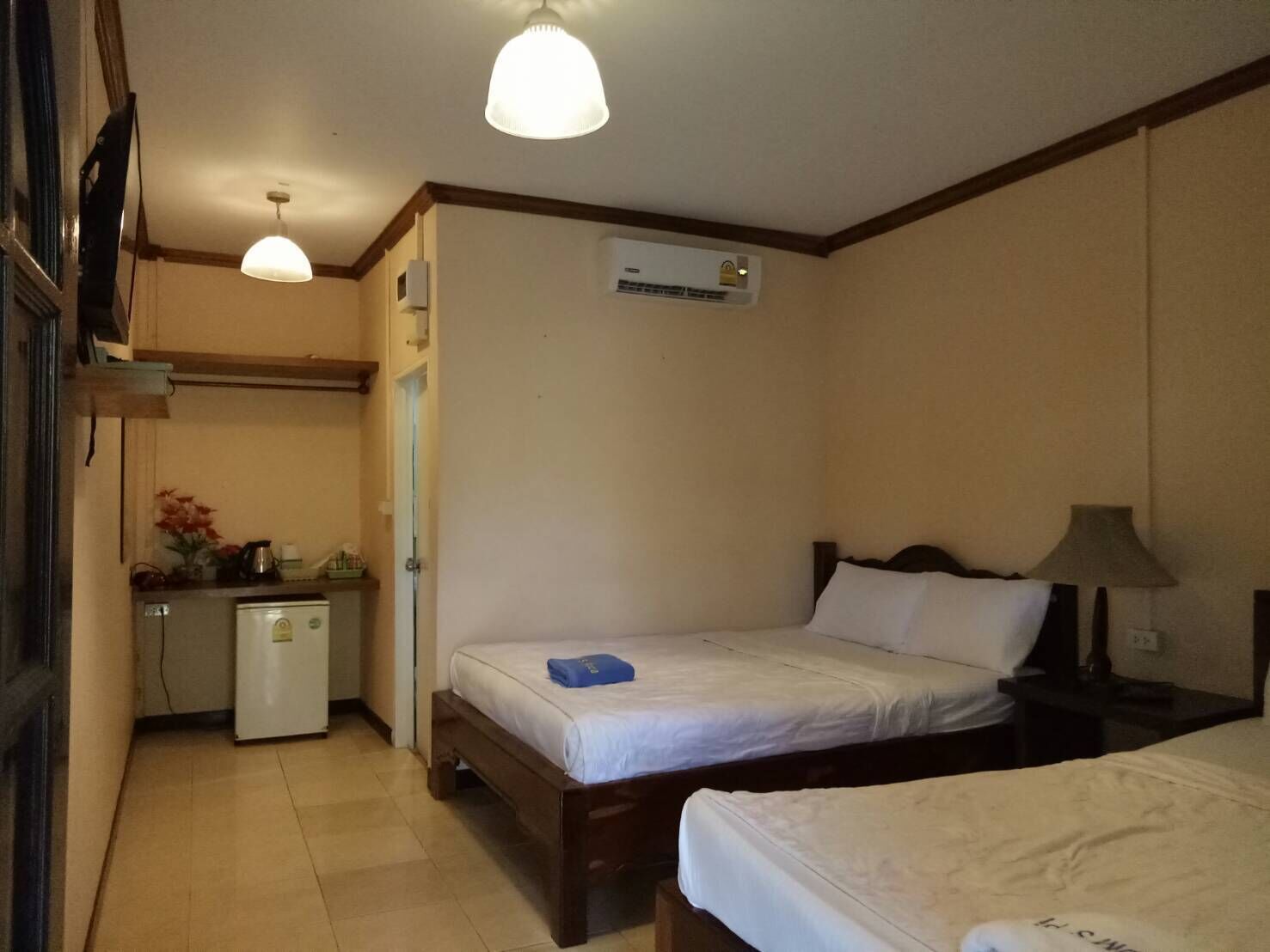Una habitación de hotel con dos camas, un escritorio, un refrigerador y aire acondicionado.