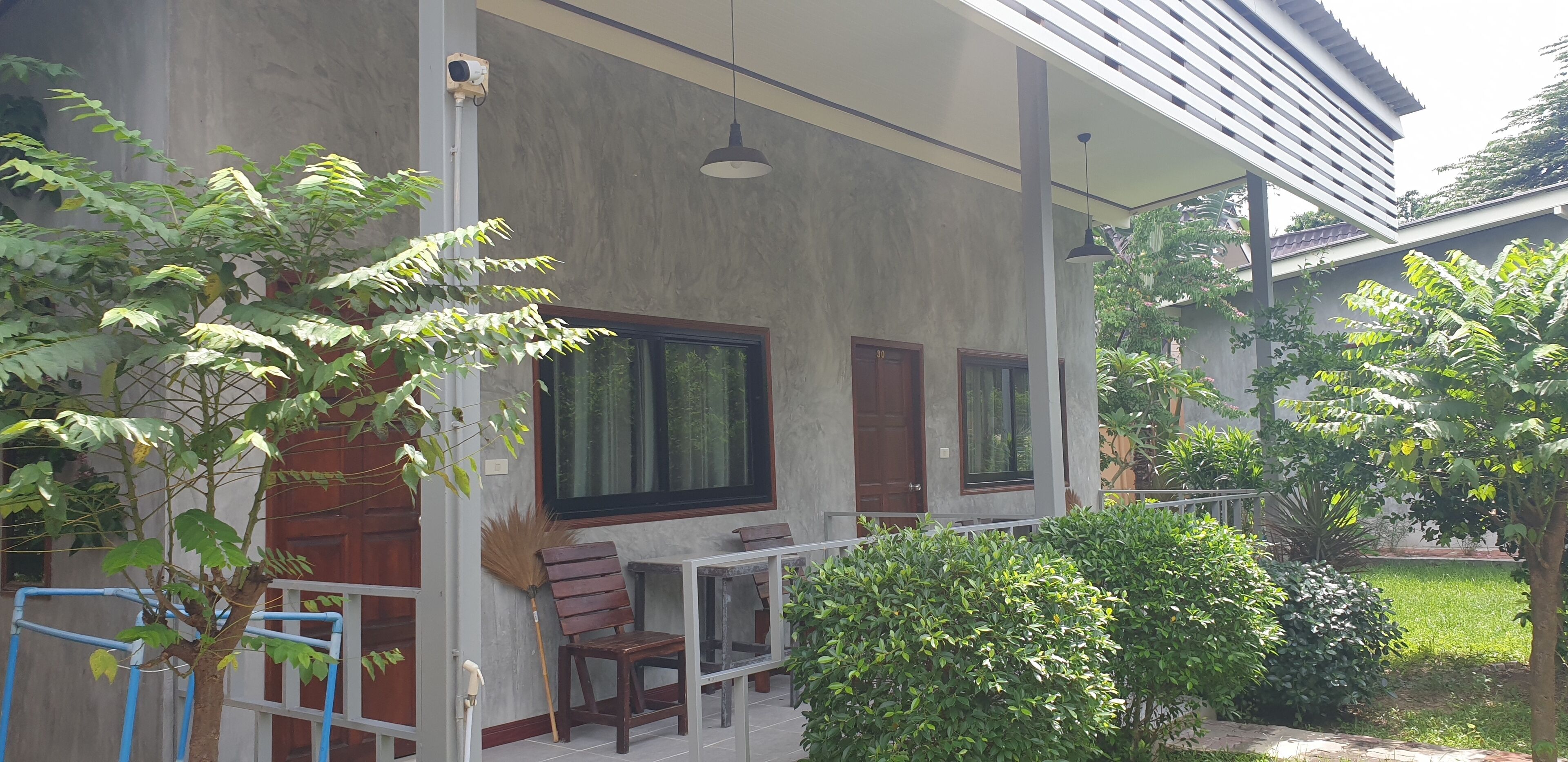 A building with a covered outdoor area featuring a table and chairs, a large window, and a door.