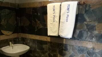 A bathroom with a stone wall, a sink, a toilet, and a shower.