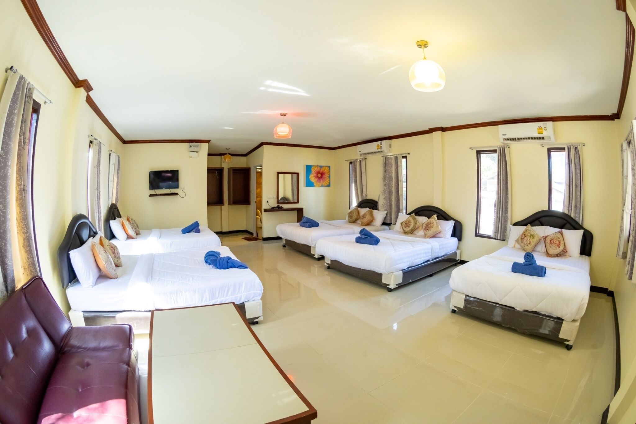A hotel room with three beds, a TV, and an air conditioning unit.