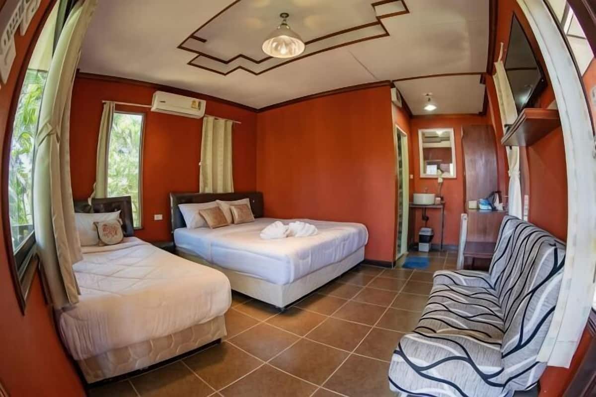 A room with two beds, a sofa, a ceiling fan, and a window.