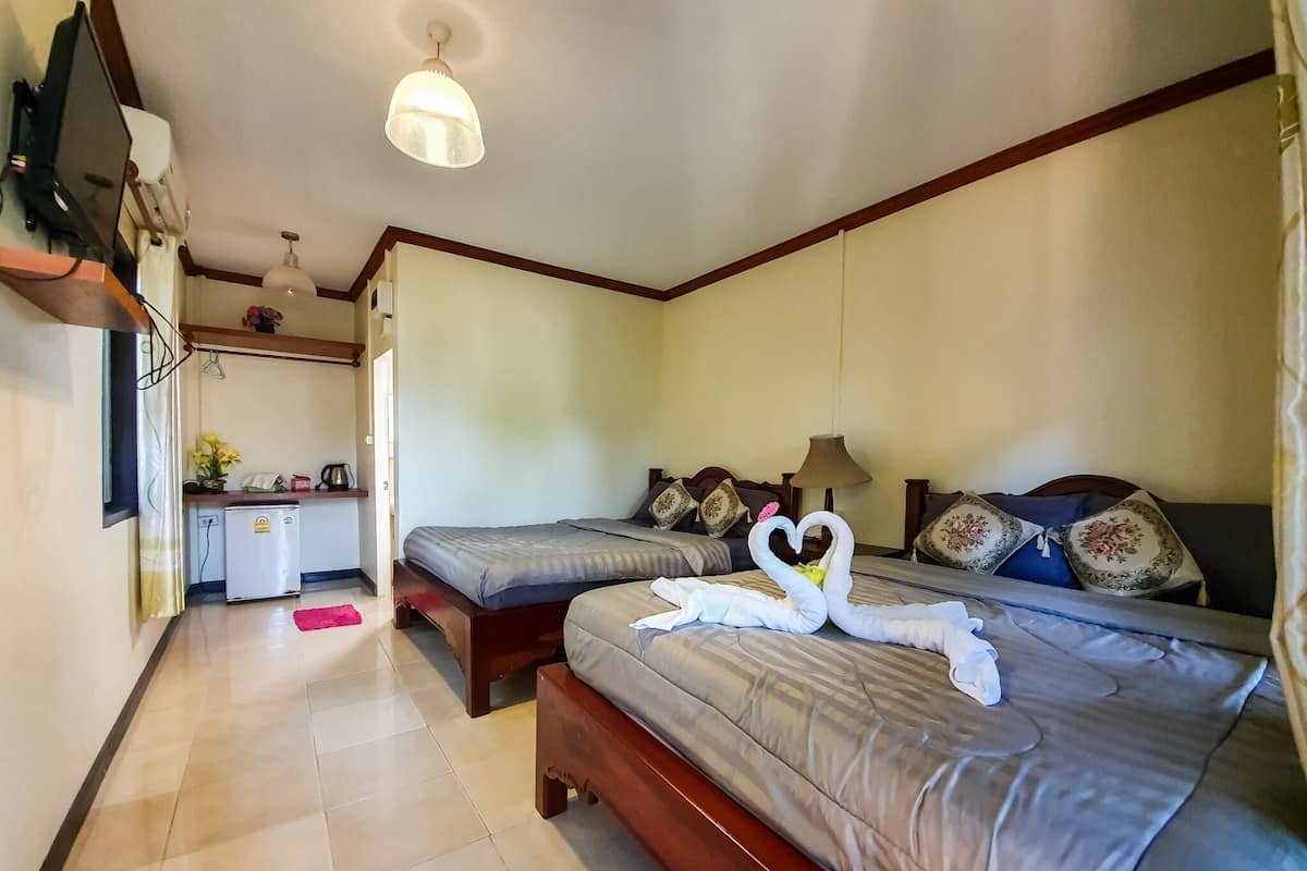 A hotel room with two beds, a small kitchenette, and a ceiling fan.