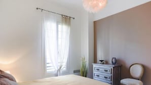 A bedroom with a bed, a dresser, a chair, and a window with curtains.