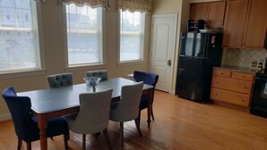 A dining area with a table and chairs, a refrigerator, and wooden cabinets in a kitchen. - Spacious Yet Cozy Edgewater Park Townhouse (Minutes to the Boardwalk) (Rehoboth Beach)