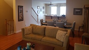 A living room with a sofa, coffee table, and a dining area with chairs and a table. - Spacious Yet Cozy Edgewater Park Townhouse (Minutes to the Boardwalk) (Rehoboth Beach)