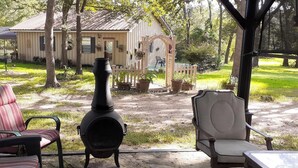 Un espacio de estar techado al aire libre con dos sillones y un estufa de leña.