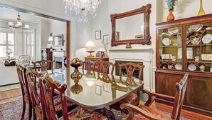 A dining room with a large glass table surrounded by ornate chairs, a chandelier, a fireplace, and a china cabinet. - Exquisite Estate on Broughton Street! (Savannah)