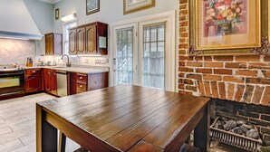 A kitchen with wooden cabinets, a dining table, and a brick fireplace.