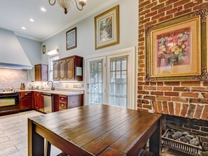 A kitchen with wooden cabinets, a dining table, and a brick fireplace.