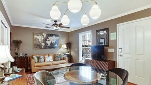 A dining area with a glass table, cushioned chairs, a ceiling fan, and a chandelier. - Lovely Carriage House In the Middle of Downtown! (Savannah)