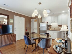 Enjoy meals and relaxation in this well-equipped kitchen and dining area with a round table, comfortable seating, and a mounted TV.