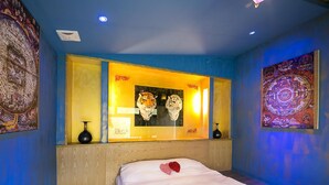 Una camera d'albergo con un letto, uno specchio grande e opere d'arte alle pareti.