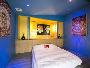 Ein Hotelzimmer mit einem Bett, einem großen Spiegel und Kunstwerken an den Wänden.