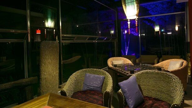 Interno di un ristorante con mobili in vimini, un tavolo in legno e un lampadario.