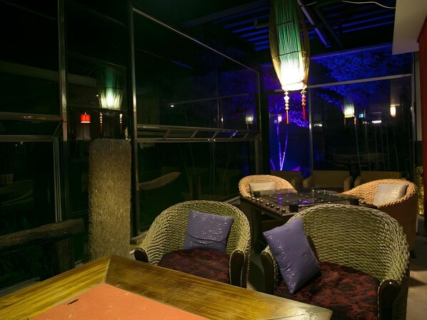 Ein Restaurantinneres mit Korbmöbeln, einem Holztisch und einer hängenden Leuchte.