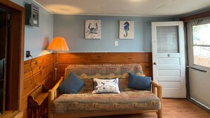 A cozy room with a wooden bench, a sofa with blue cushions, and a door marked with the number 5. -  #5-The Lazy Fish (Au Sable Charter Township)